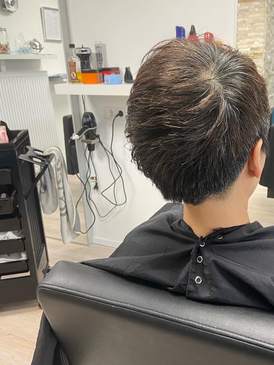 Kort donker kapsel, van achteren gezien in de salon